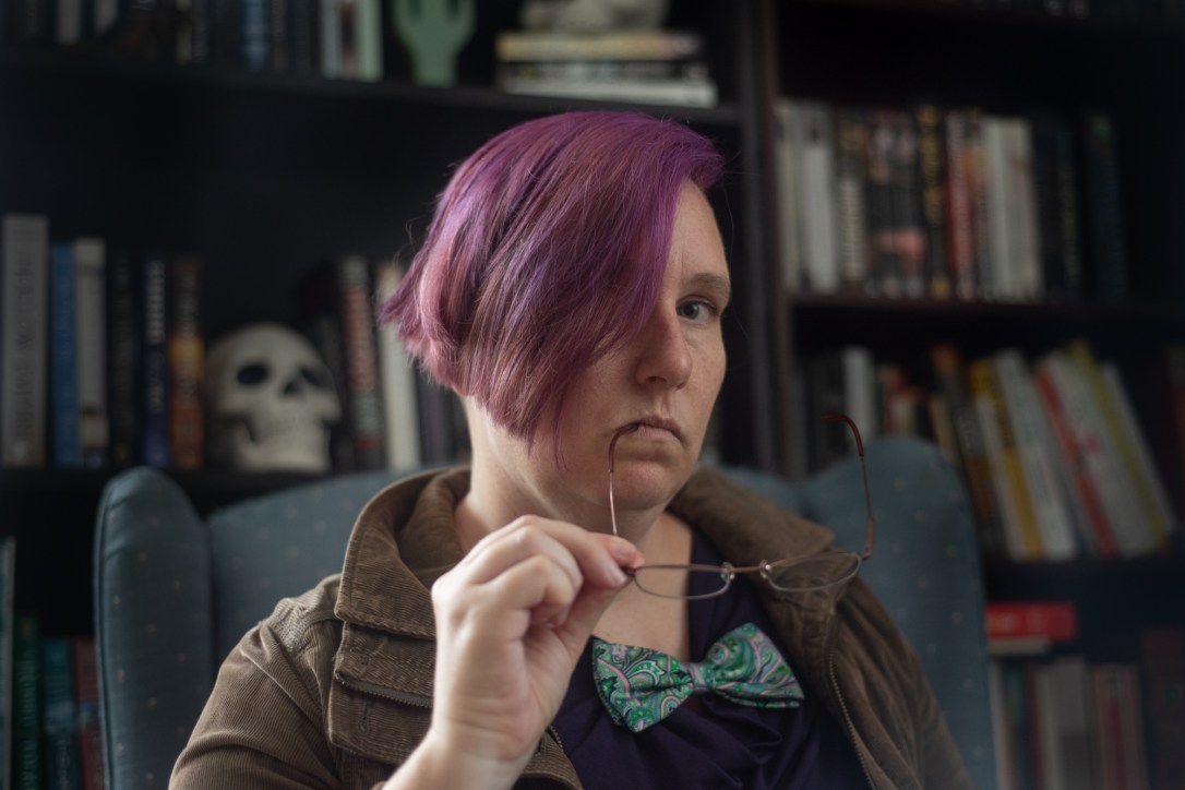 The Author wearing a dapper jacket in front a bookcase with an appropriately placed skull