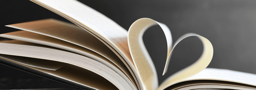 An open hardcover book with the center pages curved into a heart